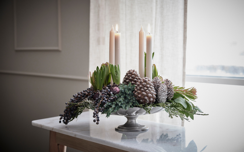 Klassischer Adventskranz mit vier weißen Kerzen, Tannenzweigen und Zapfen